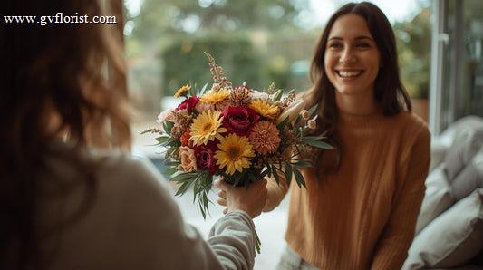 A person handing a fresh flower bouquet to another person as a thank-you gesture, showing appreciation and kindness
